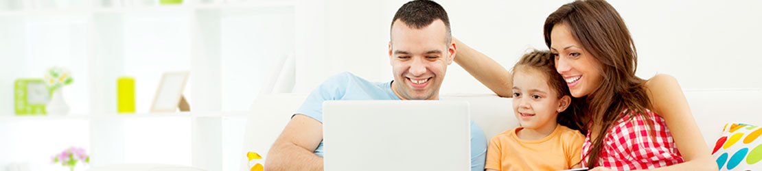 Family of three looking over laptop computer together.